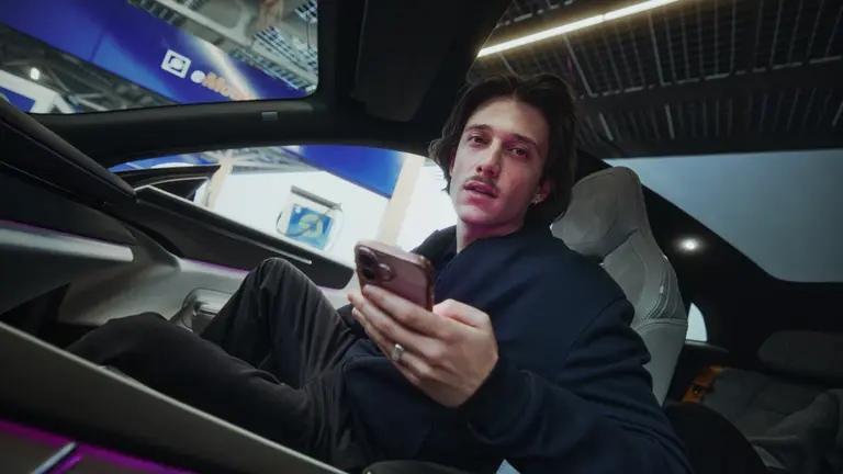 ein mann sitzt im auto und hält ein handy in der hand
