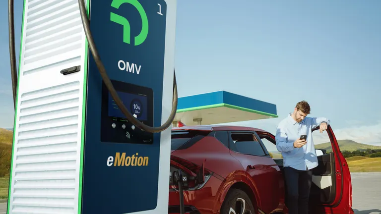 Zu sehen ist die neue eMotion Ladesäule und ein Mann mit einem roten Auto im Hintergrund