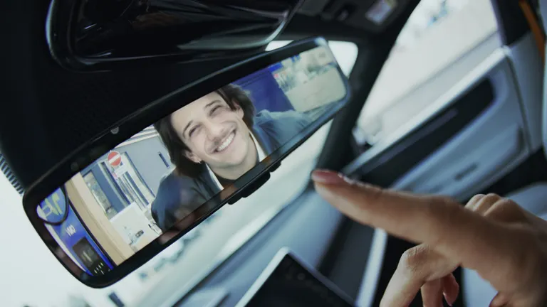 ein finger zeigt auf den rückspiegel im auto und sieht einen freund beim eMotion Charger stehen