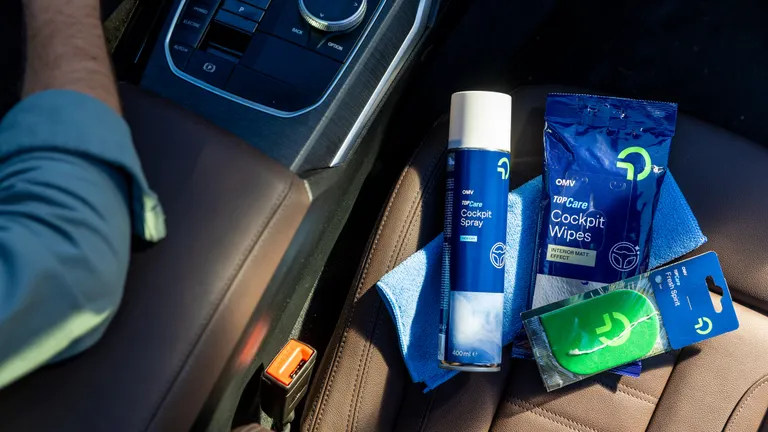 Ein Autopflegeset liegt auf einem braunen Leder-Beifahrersitz 