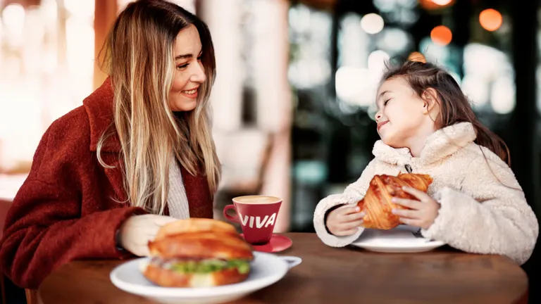 Ein gefülltes Baguette, ein Schokocroissant und Cafe in To-Go Becher und Tasse